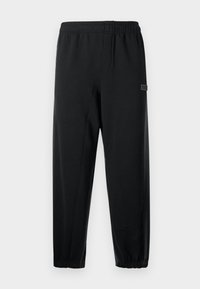 Calças de treino pretas com uma cintura elástica, pernas afuniladas e um pequeno logótipo. Feitas de um tecido suave e leve.