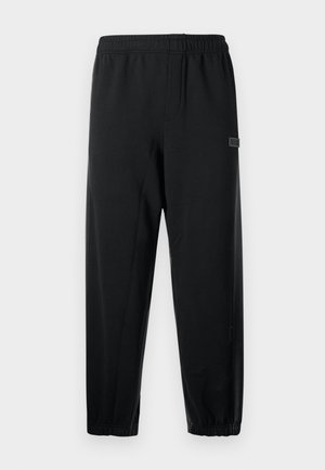 Calças de treino pretas com uma cintura elástica, pernas afuniladas e um pequeno logótipo. Feitas de um tecido suave e leve.