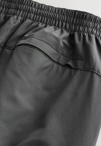 Graue Sportkurzshorts mit elastischem Bund, glatter Textur und einer Gesäßtasche mit minimalen Nähdetails.