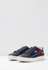 Navy leather sneakers with embroidered floral design in red and green, contrast laces, and white rubber soles. Smooth and textured finish.