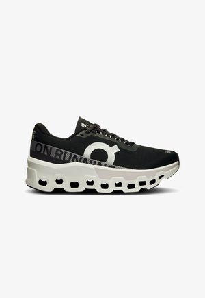 Black running shoe with a textured mesh upper, prominent white logo, and a unique white and black molded sole with hexagonal cutouts.