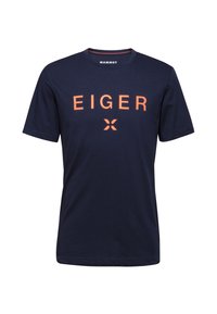 T-paita tummansinistä puuvillaa, jossa on oranssi "EIGER" -teksti ja logo. Lyhyet hihat ja pyöreä kaula-aukko, pehmeä rakenne.