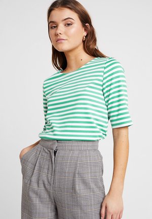 Grün-weiß gestreiftes kurzärmliges T-Shirt aus weichem Stoff, kombiniert mit hoch taillierten grauen Karohosen mit Falten und seitlichen Taschen.