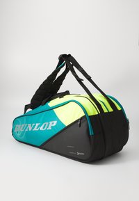 Dunlop Reisetasche mit schwarzem Boden, türkisfarbenem oberen Teil und leuchtend gelben Akzenten. Verfügt über gepolsterte Schultergurte und mehrere Reißverschlusstaschen.