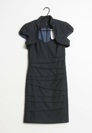 Robe gris foncé longueur genou avec plis horizontaux superposés, manches courtes bouffantes, encolure découpée et col boléro fixé sur un cintre noir.