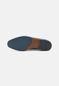 Suela de zapato con una base de goma azul, texturizada para proporcionar agarre, con un acento de cuero marrón en el talón y un diseño elegante.