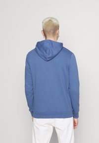 Modrá bavlněná mikina s kapucí na šňůrku, žebrovanými manžetami a spodním lemem. Hladká textura, neformální design a volný střih.
