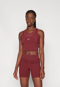 Ensemble de débardeur et short sport bourgogne. Le débardeur a un col rond et un détail de logo ; le short présente une taille large avec des accents texturés.