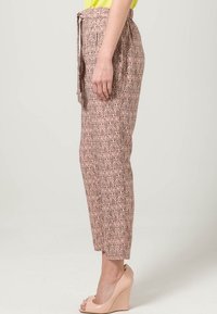 Kostkované zúžené kalhoty v světlé růžové barvě s páskem na zavazování, obsahující geometrický vzor a hladkou texturu, spárované s nahými klínovými podpatky.