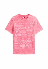Różowa bawełniana koszulka z wygaszoną farbą, z wieloma białymi logo tekstowymi, w tym "TOMMY JEANS" oraz "University Club", w różnych czcionkach.