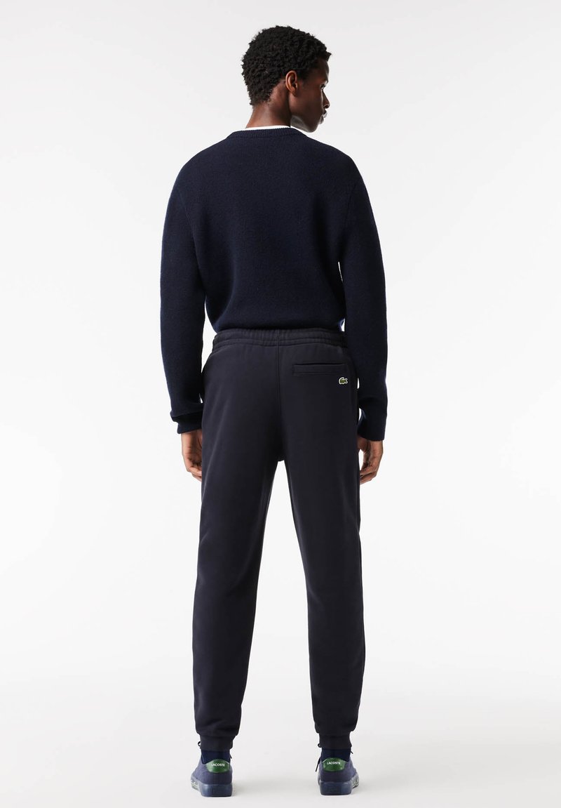 Pull marin avec col rond, accompagné d'un pantalon de jogging assorti à taille élastique et avec une poche arrière. Détail de logo en accent.