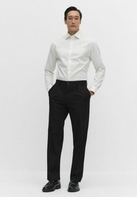 Overhemd met witte en lichtgrijze strepen, combineert met zwarte broek en zwarte instapschoenen, gepresenteerd op een neutrale achtergrond.