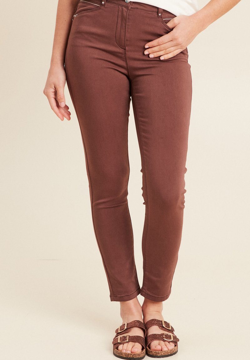 Bruine skinny jeans van een katoenmix, met een middelhoge taille, voorzakken en een gladde textuur. Gepaard met bruine sandalen.
