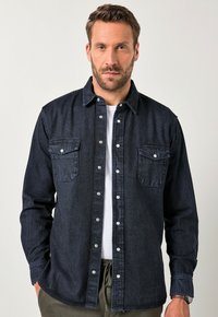 Camicia in denim scuro con chiusura a bottoni, due tasche sul petto e bottoni a pressione argentati. Presenta un colletto strutturato e maniche lunghe.
