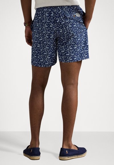Navy shorts med et hvitt blomster mønster, laget av lett materiale. Inkluderer sidelommer, en baklomme og knappelukking.