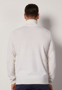 Maglione bianco a maglia con colletto alto, caratterizzato da maniche lunghe e una texture liscia; design minimalista senza motivi o logo visibili.