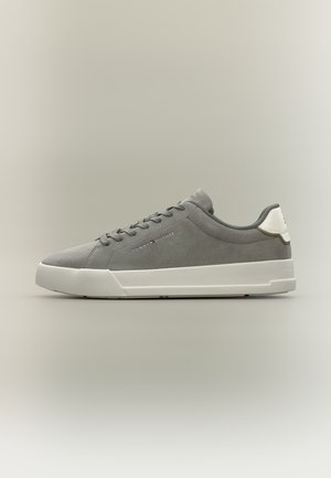Sneaker basse in camoscio grigio con suola bianca e linguetta sul tallone, design con lacci e piccolo logo Tommy Hilfiger sul lato.
