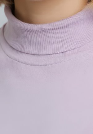 Gros plan sur une personne portant un pull à col roulé côtelé de couleur violet clair, mettant l'accent sur le cou et la zone du col.