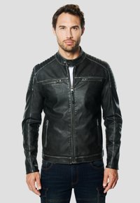 Zwarte leren jas met ritssluiting aan de voorkant, twee zijzakken, geribbelde schouderdetails en een opstaande kraag. Soepele textuur en getailleerd ontwerp.