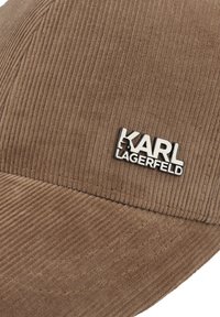 Cappello in velluto a coste marrone con un design cucito e un dettaglio in metallo con il logo "KARL LAGERFELD". La texture è a coste, con una visiera curva.
