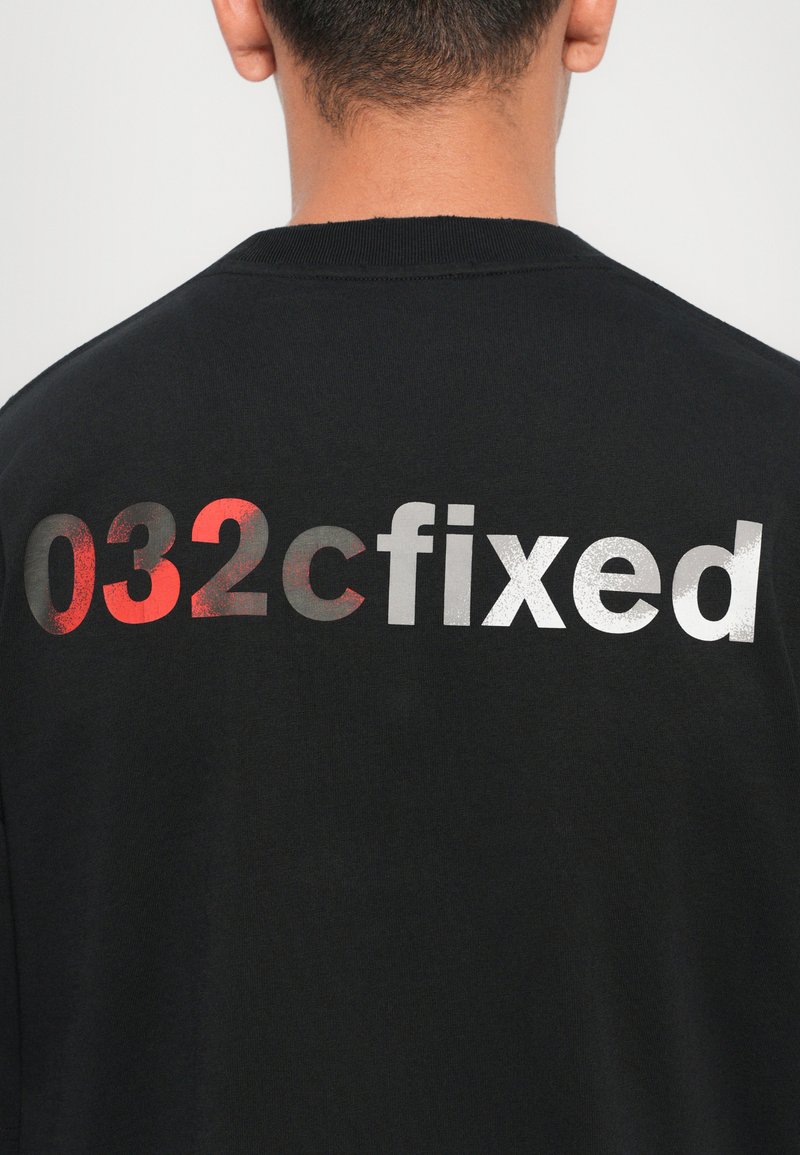 Schwarzes Crewneck Sweatshirt mit einem großen, mehrfarbigen Druck auf dem Rücken, der den Text "032cfixed" in Rot und Silber zeigt.