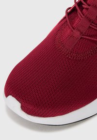 Maroons athletic sko med en åndbar mesh-overdel, struktureret overflade og hvid gummisål. Har snørelukning for en sikker pasform.