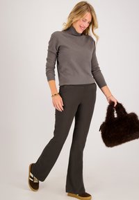 Grijze, fitted coltrui met lange mouwen, gecombineerd met donkerbruine flared pantalons. Accentuated met een bruine nepbont handtas en bruine schoenen.