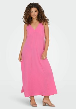 Rosa maxiklänning med V-ringning, ärmlös design, flödande tyg och sidoknäm. Bärs med ljusbruna klacksandaler.