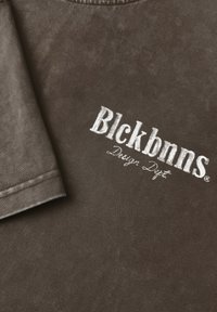 Bruine katoenen t-shirt met een geborduurd wit logo "Blckbnns Design Dept." Soepele textuur met een ronde hals en kort mouw ontwerp.