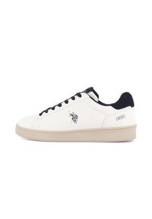 Baskets basses blanches avec lacets noirs, col rembourré noir, semelle beige et petit logo joueur de polo sur le côté.