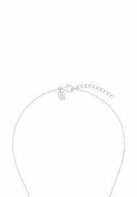 Silberne Kettenarmband mit einem Karabinerverschluss und verstellbarer Länge. Es hat einen kleinen Anhänger mit einem Logo, eine glatte Textur und ein minimalistisches Design.