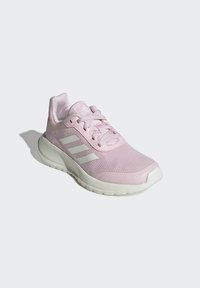 Scarpa da ginnastica rosa chiaro con superiore in mesh, colletto imbottito e suola in gomma bianca. Presenta tre strisce laterali bianche e lacci tono su tono.