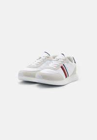 Zapatillas blancas con acentos de ante, que presentan franjas rojas y marino. Tejido texturizado y suela lisa, diseño de punta redonda con cordones.