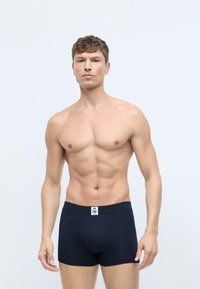 Boxershorts i mørk navy stof med en blød tekstur. Har et logo-patch på taljen. Pasformen er skræddersyet og tætsiddende.