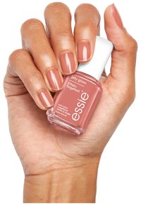Le vernis à ongles Essie Jelly Gloss dans une teinte rose clair, tenu dans une main, avec une finition brillante et un bouchon blanc, accompagnée de doigts bien manucurés.