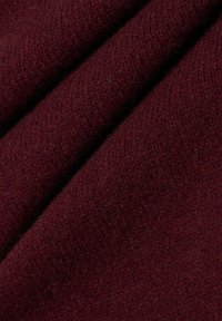 Bordeaux stof met een zachte, textuurachtige oppervlakte, gekenmerkt door subtiele weefpatronen die de warmte en pluche uitstraling versterken.