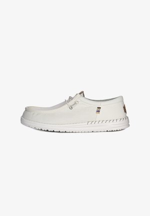 White canvas shoe with a rounded toe, lace-up design, and a textured sole. Features subtle colored accents and a stitched edge.