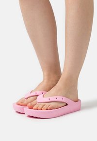 Infradito rosa in gomma con design a V, dotate di fori laterali, suola piatta e impugnatura texturizzata per una maggiore stabilità.