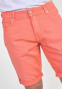 Koraalkleurige denim short met een omgeslagen zoom, voorzien van een knoopsluiting en een ontwerp met vijf zakken, gemaakt van een gladde en iets gestructureerde stof.