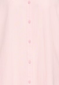 Tissu rose doux avec une rangée verticale de cinq petits boutons ronds, chacun avec quatre trous, espacés uniformément au centre.