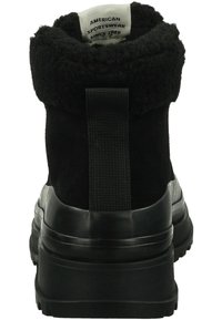 Schwarze Knöchelstiefel mit einem flauschigen schwarzen Saum, Gummisohle und strukturiertem Absatz. Mit einem Zugband hinten für ein einfaches Anziehen.