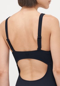 Fato de banho preto com nervuras, alças ajustáveis e detalhe das costas em recorte, apresentando costuras planas e um design elegante. O material parece elástico.