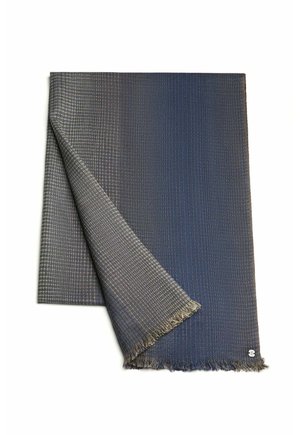 Textile blanket in gradient blue and gray hues, featuring a woven texture and frayed edges, with a small logo in the corner.