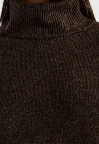 Maglione a collo alto marrone realizzato in tessuto a costine, caratterizzato da un colletto alto e una texture morbida, adatto per essere indossato a strati o per un look casual.