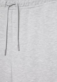 Pantaloni de trening gri deschis cu talie elastică și șnur asortat legat într-un nod în față.