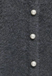 Temno siva volnena jopica z nežno teksturo in tremi belimi bisernimi gumbi spredaj. Preprost dizajn brez dodatnih vzorcev.