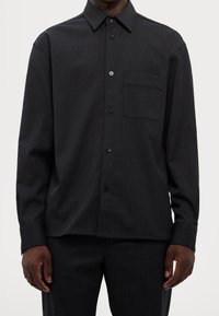 Zwarte button-up overhemd met een kraag, enkele borstzak en lange mouwen. Gladde textuur en regular fit ontwerp.