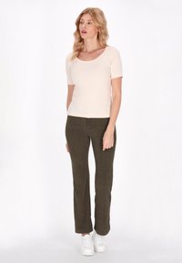 Korte mouwen lichtbeige top, gecombineerd met olijfgroene corduroy broek, aangevuld met witte sneakers. Eenvoudig design met een aansluitende pasvorm.