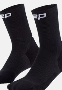 Calzini sportivi neri con texture a coste e punta rinforzata. Presenta il logo bianco sul risvolto. Design di lunghezza a metà polpaccio per il massimo comfort.