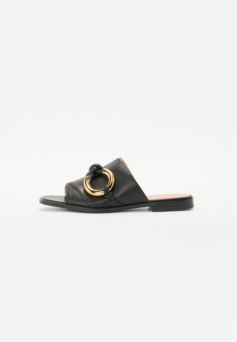 Svarta läder sandaler med knutna remmar och dubbla guldringar som accent. Har en platt sula och öppen tåsdesign.